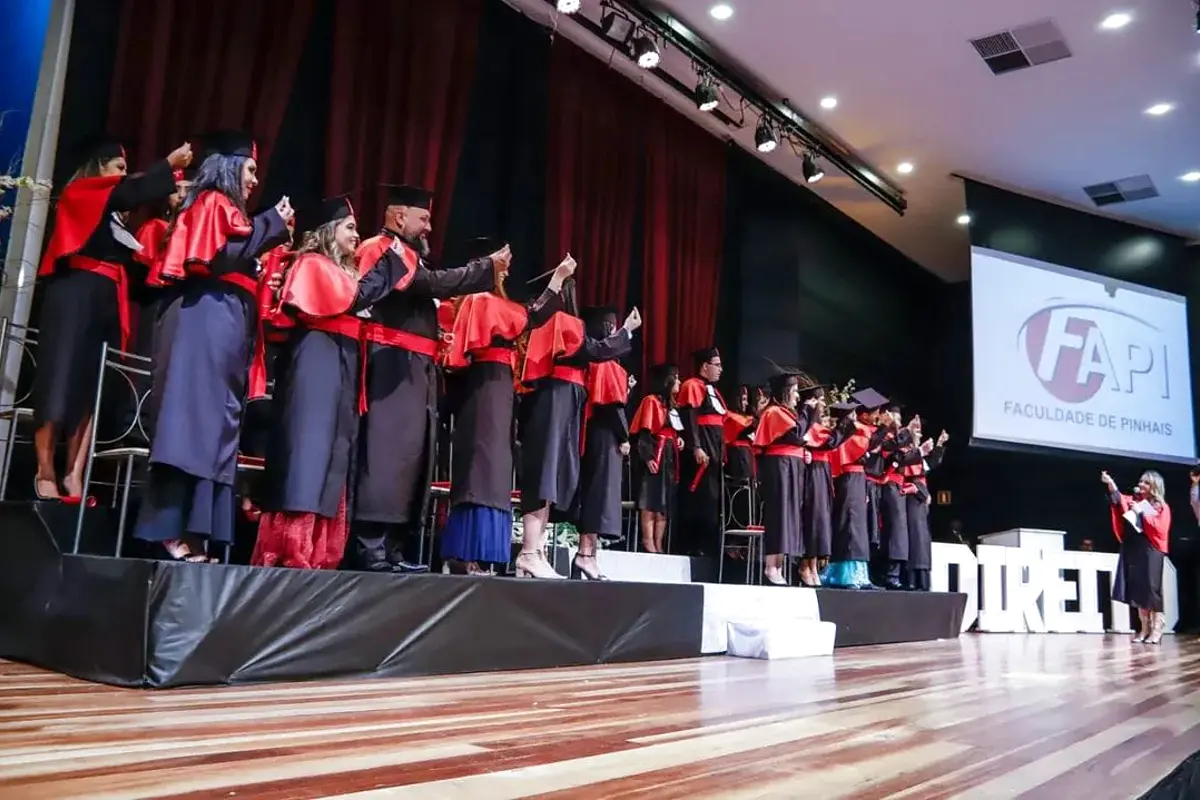 Formatura com formandos no palco, iluminação cênica e projeção
